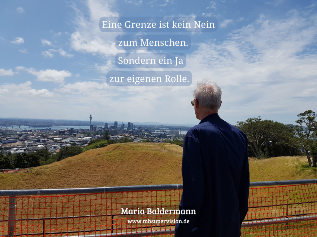 Ein Mann schaut von einem Hügel auf eine Stadt. Darüber der Text: Eine Grenze ist kein Nein zum Menschen. Sondern ein Ja zur eigenen Rolle.