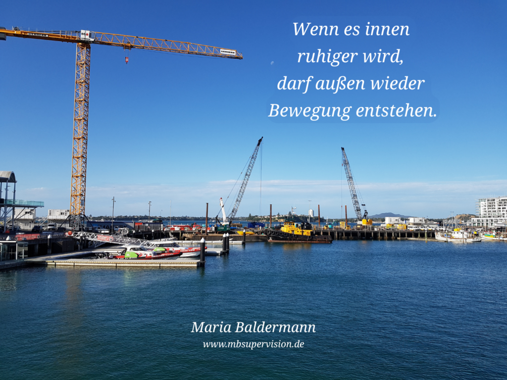 Hafenansicht mit Kränen. Dazu der Text: Wenn es innen ruhiger wird, darf außen wieder Bewegung entstehen.