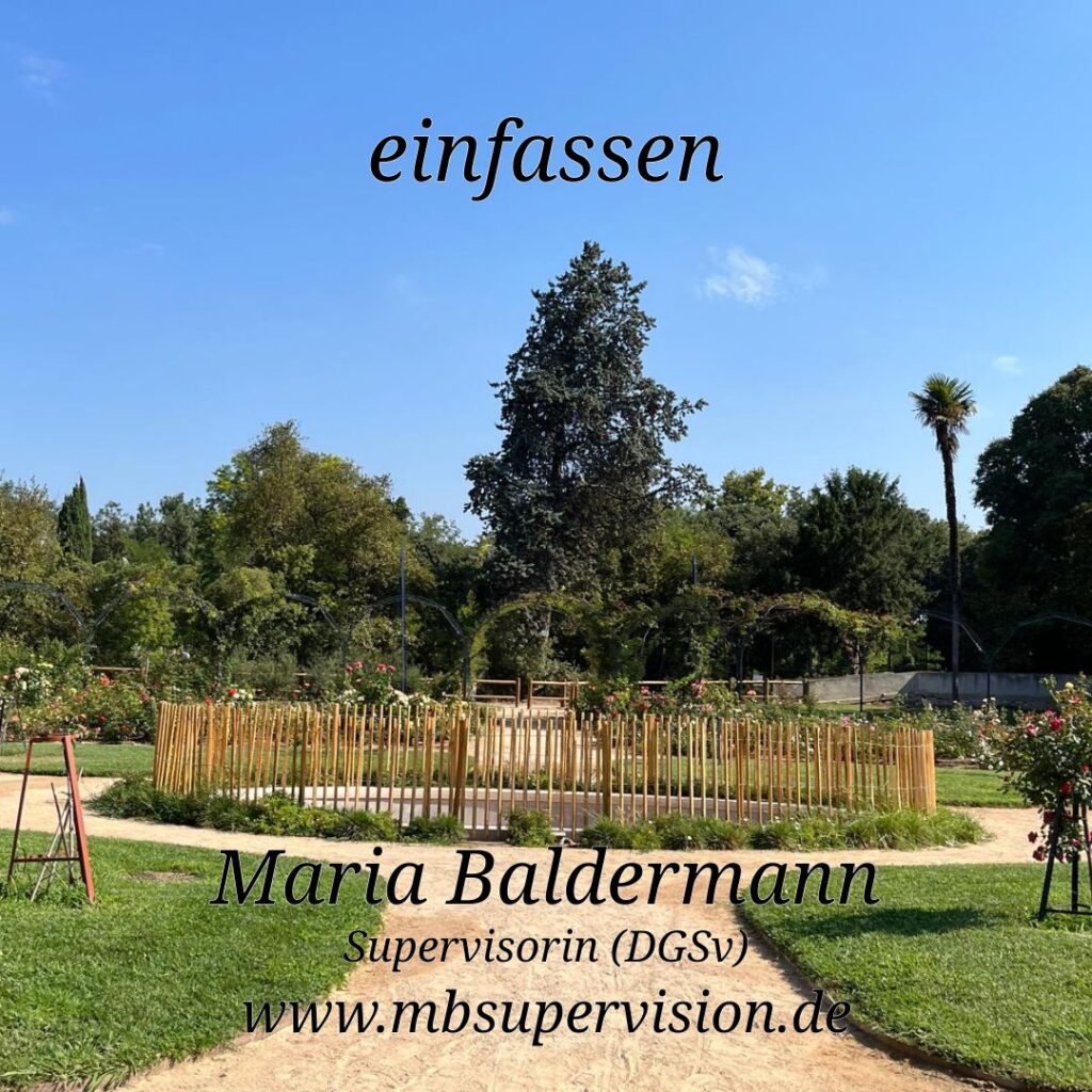 Durch eine gepflegte Gartenanlage verläuft ein heller Kiesweg. In der Mitte ist ein runder Bereich von einem niedrigen, hellen Holzzaun eingefasst. Das Bodenniveau innerhalb des Bereichs scheint unterhalb des Äußeren zu liegen. Hinter dem Bereich sind zahlreiche Bäume und Sträucher zu sehen, Der Himmel ist klar und blau. Im oberen Bereich steht der Schriftzug 'einfassen', Unten im Bild sind der Name 'Maria Baldermann', die Berufsbezeichnung 'Supervisorin (DGSV)' und die Internetadresse 'www.mbsupervision.de' zu lesen.