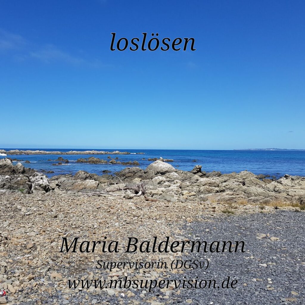 Im Vordergrund ein steiniger Strand mit vereinzelten größeren Felsen. Dahinter liegt das ruhige, tiefblaue Meer, das bis zum Horizont reicht. Der Himmel ist fast wolkenlos und kräftig blau. Oben steht das Wort 'loslösen'. Unten im Bild sind der Name 'Maria Baldermann', die Berufsbezeichnung 'Supervisorin (DGSV)' und die Internetadresse 'www.mbsupervision.de' zu lesen.