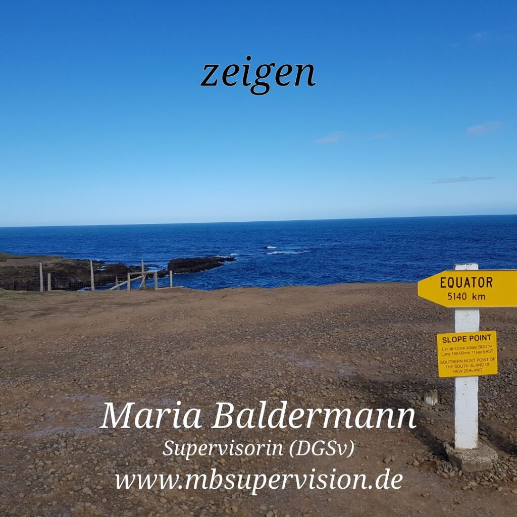 Weitläufige felsige Küstenlandschaft mit blauem Meer und klarem Himmel. Rechts im Vordergrund ein gelbes Wegweiser-Schild mit der Aufschrift „EQUATOR 5140 km“ und Hinweisen zum „SLOPE POINT“. Oben in Bild steht das Wort 'zeigen'. Unten im Bild sind der Name 'Maria Baldermann', die Berufsbezeichnung 'Supervisorin (DGSV)' und die Internetadresse 'www.mbsupervision.de' zu lesen.