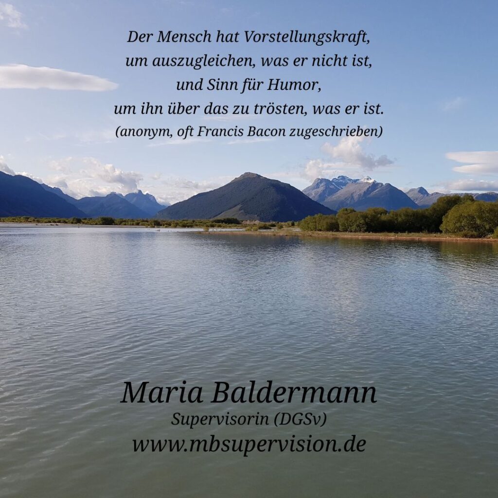 Im Vordergrund erstreckt sich ein ruhiger See mit sanften Wellen. Dahinter liegt eine grüne Wiesenlandschaft, die in eine Bergkette mit schneebedeckten Gipfeln übergeht. Der Himmel ist klar und blau, nur wenige Wolken sind zu sehen. Im oberen Bildbereich steht mittig ein Zitat: 'Der Mensch hat Vorstellungskraft, um auszugleichen, was er nicht ist, und Sinn für Humor, um ihn über das zu trösten, was er ist. (anonym, oft Francis Bacon zugeschrieben)'. Unten im Bild sind der Name 'Maria Baldermann', die Berufsbezeichnung 'Supervisorin (DGSV)' und die Internetadresse 'www.mbsupervision.de' zu lesen.