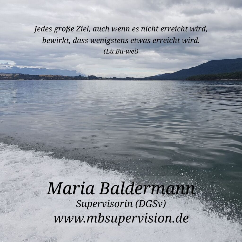 Wellen auf einem ruhigen See mit Bergen am Horizont. Der Himmel ist bewölkt, aber hell. Im oberen Bildteil ist ein Zitat eingeblendet: 'Jedes große Ziel, auch wenn es nicht erreicht wird, bewirkt, dass wenigstens etwas erreicht wird. (Lü Bu-wei)'. Unten im Bild sind der Name 'Maria Baldermann', die Berufsbezeichnung 'Supervisorin (DGSV)' und die Internetadresse 'www.mbsupervision.de' zu lesen.